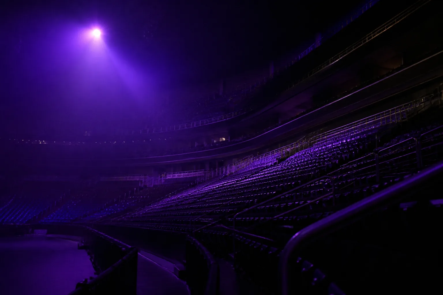 Interior de una arena de esports en penumbra con luz violeta